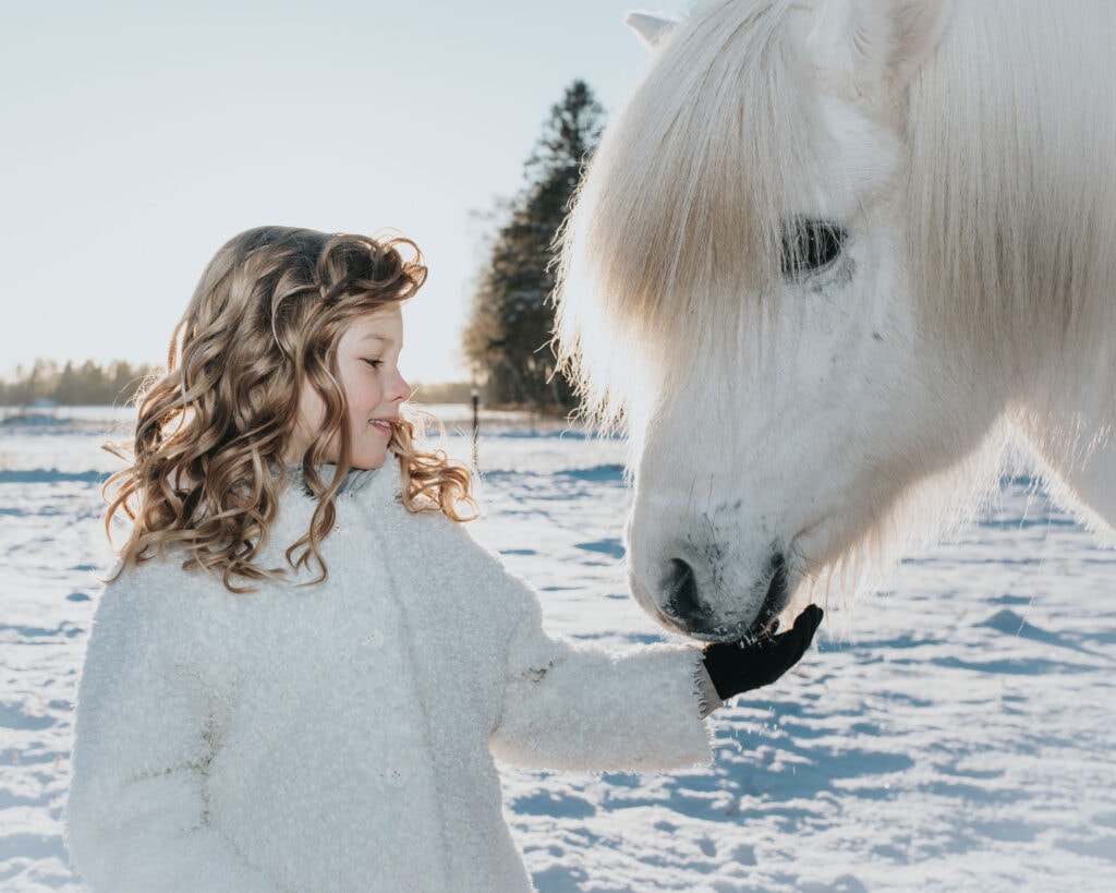 Flicka i Vinterlandskap med vit häst