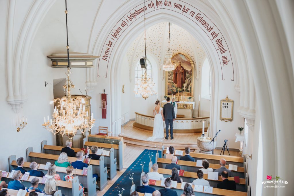 Par som gifter sig i en elegant kyrka med högt i tak och kristallkronor.