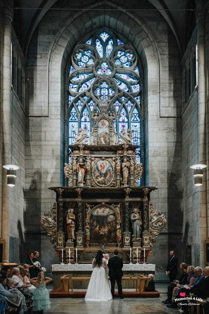 Brudpar framför altaret under en vacker bröllopsceremoni i en historisk katedral.