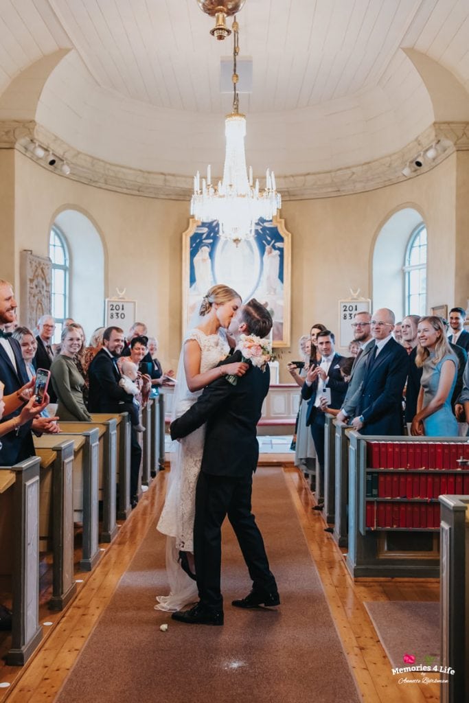 Par kysser under bröllopsceremoni i vacker kyrka 2023.