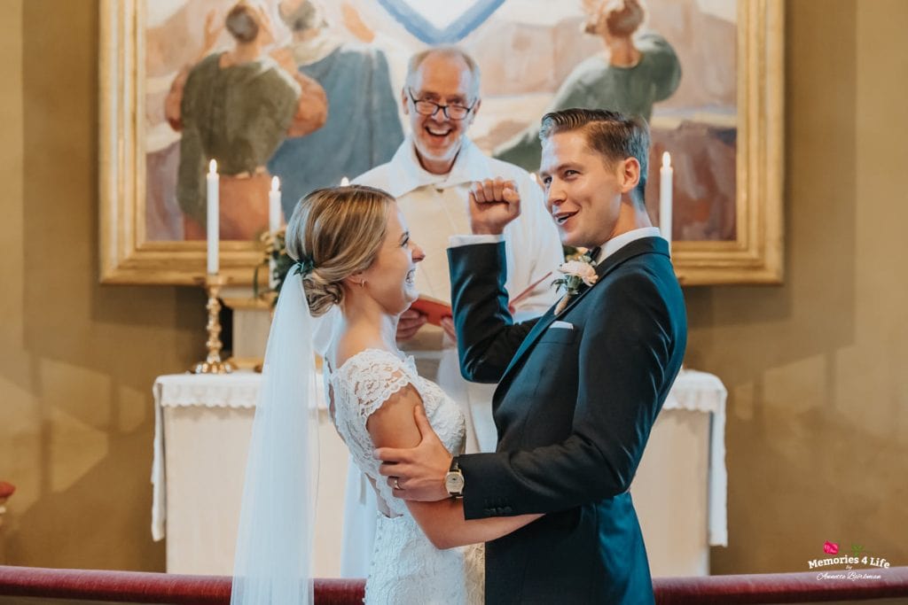 Nygifta par i kyrkan under bröllopsceremoni, glada och kärleksfulla.