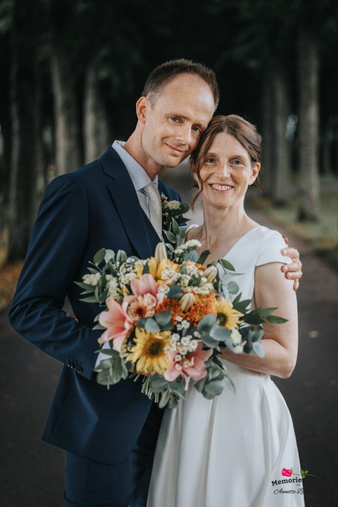 Nygift par med blomsterbukett på bröllopsdag i skogen.