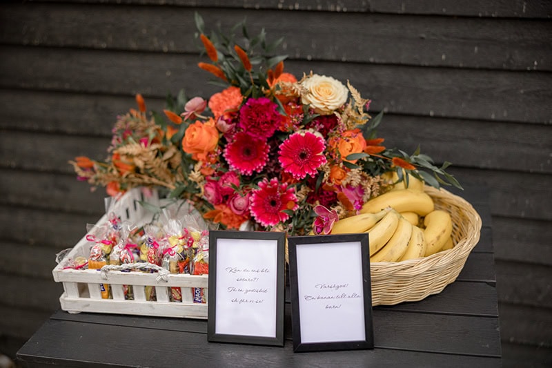 Blommor, bananer och godis på bord utanför kapellet